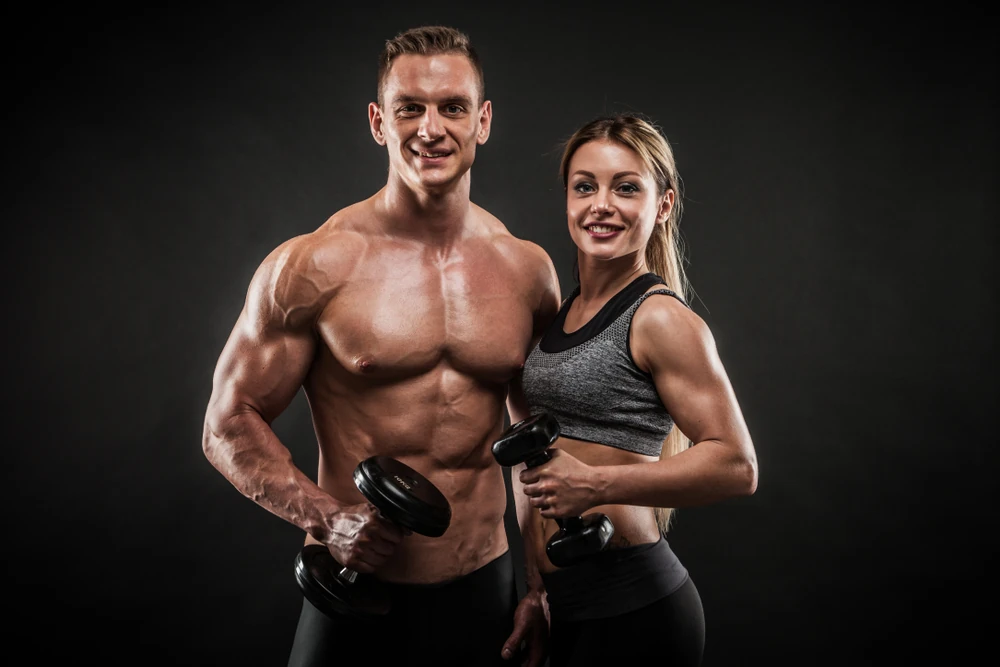 Sporty Young Couple With Dumbbells On Black Background