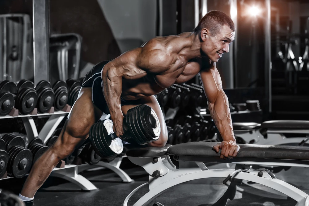 Athlete Muscular Bodybuilder Training Back With Dumbbell In The Gym Omg