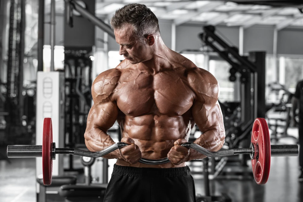 Muscular Man Workout In Gym Doing Exercises With Barbell