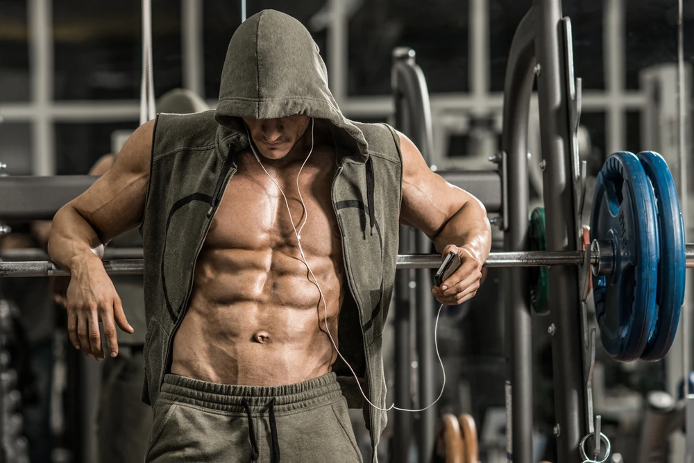 Guy Bodybuilder Tired In Gym And Listen Music With Headset